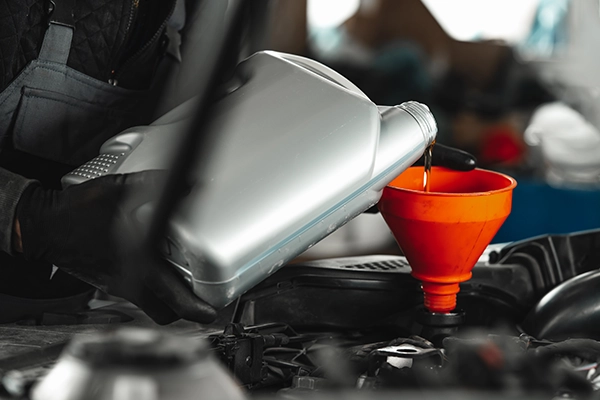 Technician filling engine with oil with orange funnel